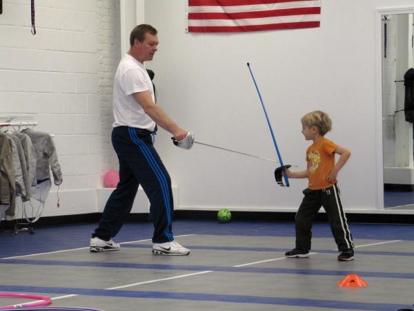 Young child learning saber fencing with a coach at Fencing Academy of Boston in Watertown, MA